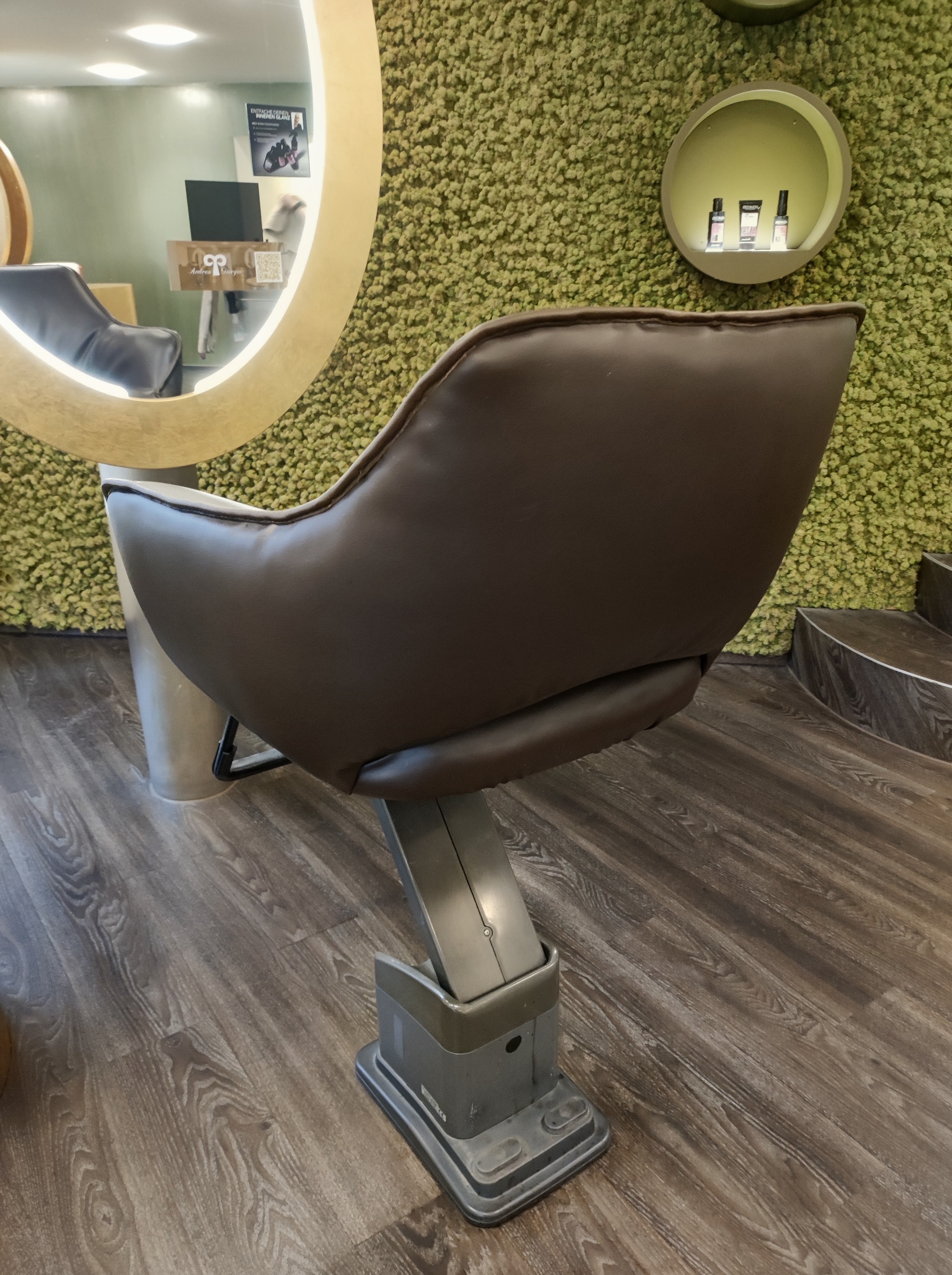 Rückansicht des neu bezogenen Coiffeur-Stuhls vor der Mooswand des Salons