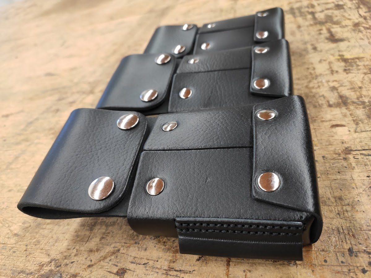 Detailaufnahme der schwarzen Lederholster mit Druckknöpfen auf der Werkbank